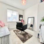 Bright salon room with black chair and mirror.