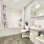 Modern bathroom with sink, bath, and toilet.