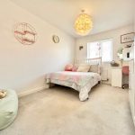 Cosy bedroom with soft furnishings and mirrored desk.