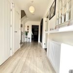 Bright hallway with wooden floor and white doors.