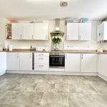 Modern kitchen with white cabinets and grey flooring.