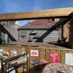 Outdoor wooden bar with vintage signs and bottles.