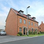 Modern brick townhouse with solar panels and driveway.