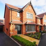 Modern red-brick house with garage and garden.