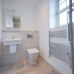 Modern bathroom with sink, toilet, and towel rail.