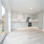 Modern kitchen with white cabinets and wooden floor.