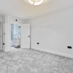 Empty carpeted room with door to bathroom.