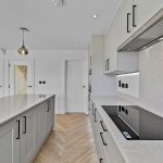 Modern kitchen with white countertops and grey cabinets.