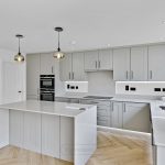 Modern kitchen with grey cabinets and marble surfaces.