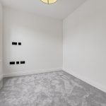 Small empty room with grey carpet and window.