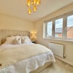 Cosy bedroom with large window and neutral decor.