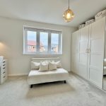 Modern bedroom with sofa and mirrored wardrobe.