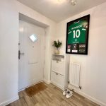 Hallway with framed jersey and wooden floor.