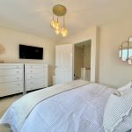 Modern bedroom with white dressers and wall mirror