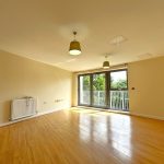 Spacious empty room with wooden floor and balcony view.