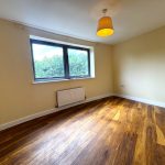 Empty room with wooden floor and large window.