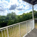 Balcony overlooking lush green trees and cloudy sky.