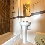 Modern bathroom with shower, sink, and toilet.