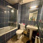 Small bathroom with blue tiles and toiletries.