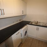 Modern kitchen with black countertops, sink, and washer.