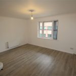 Empty room with wooden floor and large window.
