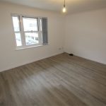 Empty room with wooden floor and window view.