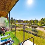Sunny balcony with bikes and green park view.