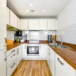 Modern white kitchen with wooden countertops.