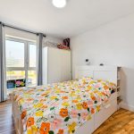 Bright bedroom with floral duvet and wooden floor.