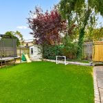 Lawn with trampoline, slide, and playhouse in garden.
