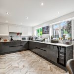 Modern kitchen with herringbone floor and large windows.
