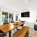 Modern dining room with wooden table and guitar.