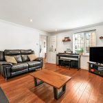 Modern living room with black leather sofas, hardwood floor.