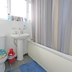 Modern bathroom with toilet, sink, and shower.