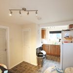 Kitchen with cabinets, fridge, and rubbish bin.