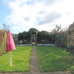 Garden with pathway, umbrellas, ivy-covered archway.