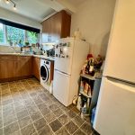 Modern kitchen with white goods and wooden cabinets.