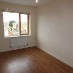 Empty room with wooden floor and large window.