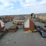 Residential neighbourhood with parked cars and houses.