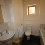 Compact bathroom with sink, toilet, and bath.