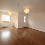 Spacious room with wooden floor and large windows.