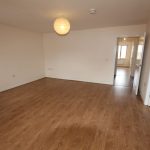 Spacious empty room with wooden flooring.