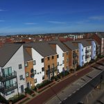 Modern UK residential housing development under blue sky.
