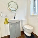 Modern bathroom with sink, mirror, and toilet.