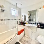 Modern bathroom with bathtub and large mirror.