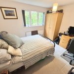 Modern bedroom with bed, desk, and gaming chair.