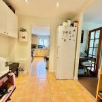 Bright kitchen with white appliances and tiled flooring.