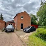 Brick house with two parked cars on driveway.
