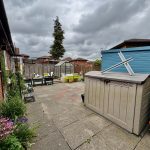Backyard with sheds, greenhouse, and patio area.