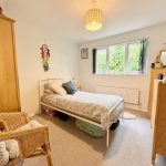 Cosy bedroom with bed, chair, TV and window view.